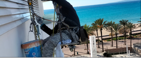 Operario Decofam con arnés trabajando en altura con mar de fondo